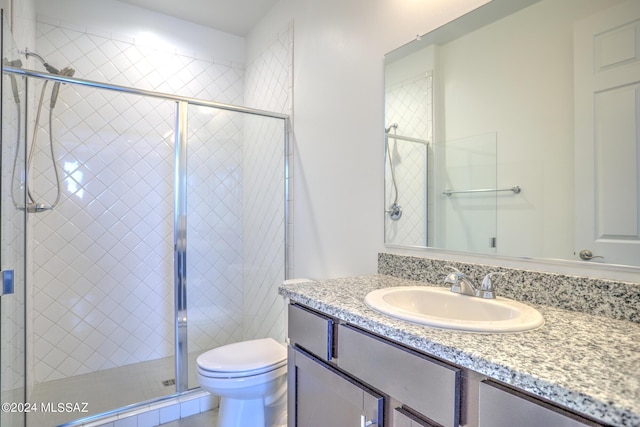 bathroom featuring vanity, a shower with shower door, and toilet