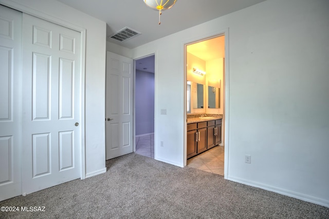 unfurnished bedroom with sink, light colored carpet, a closet, and ensuite bathroom