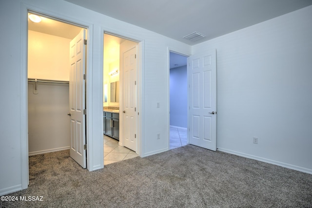 unfurnished bedroom featuring a closet, light carpet, and a walk in closet