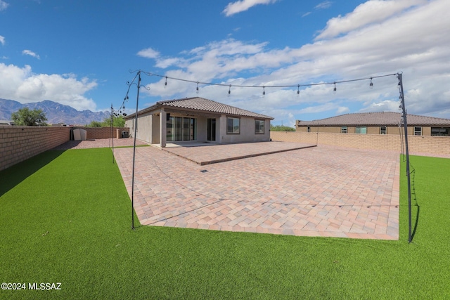 rear view of house with a mountain view, a lawn, and a patio area