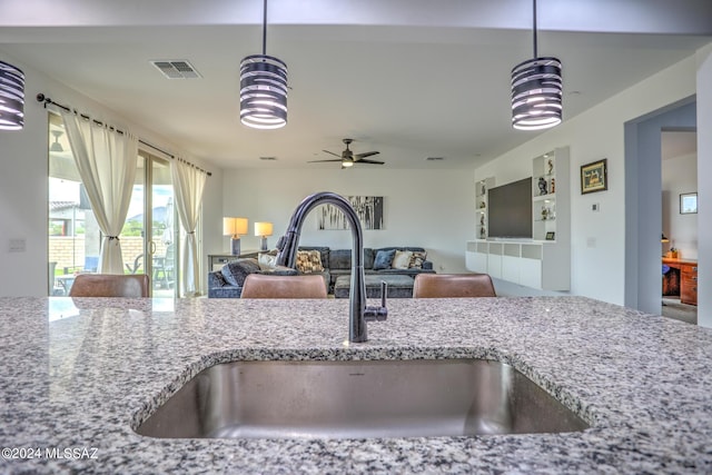 kitchen with pendant lighting, sink, and light stone counters