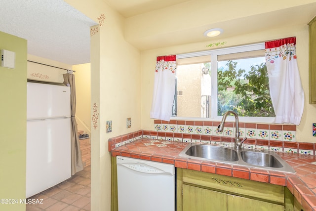 kitchen featuring tile counters, sink, backsplash, white appliances, and light tile patterned floors