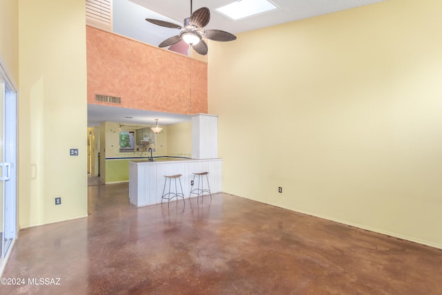 unfurnished living room with a wealth of natural light, ceiling fan, and a high ceiling