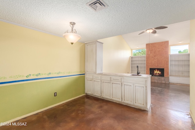 kitchen with a textured ceiling, a fireplace, sink, and decorative light fixtures