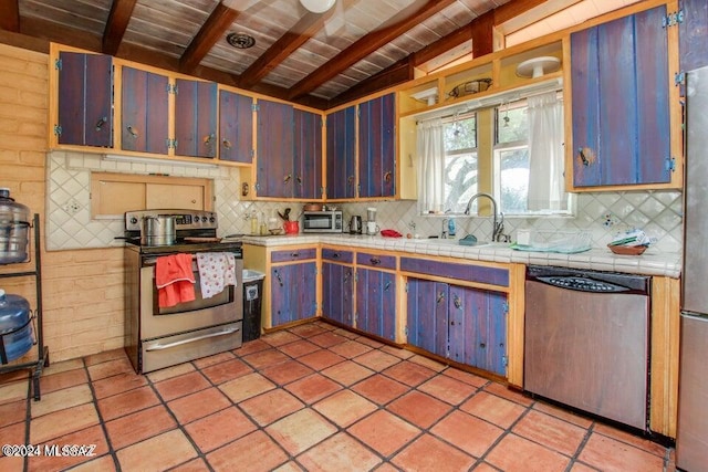 kitchen with tasteful backsplash, tile counters, appliances with stainless steel finishes, and light tile patterned floors