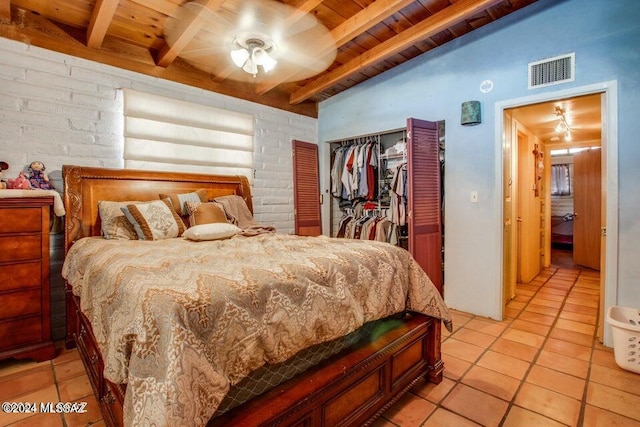 bedroom featuring light tile patterned flooring, brick wall, wooden ceiling, and a closet