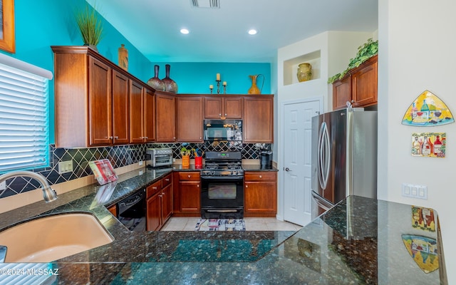 kitchen featuring kitchen peninsula, backsplash, dark stone counters, sink, and black appliances