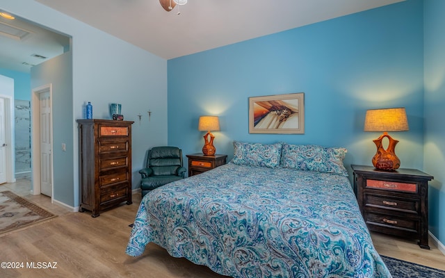 bedroom featuring light wood-type flooring, ensuite bathroom, and ceiling fan