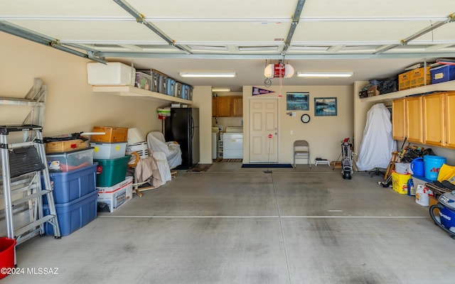 garage with black refrigerator, a garage door opener, and independent washer and dryer