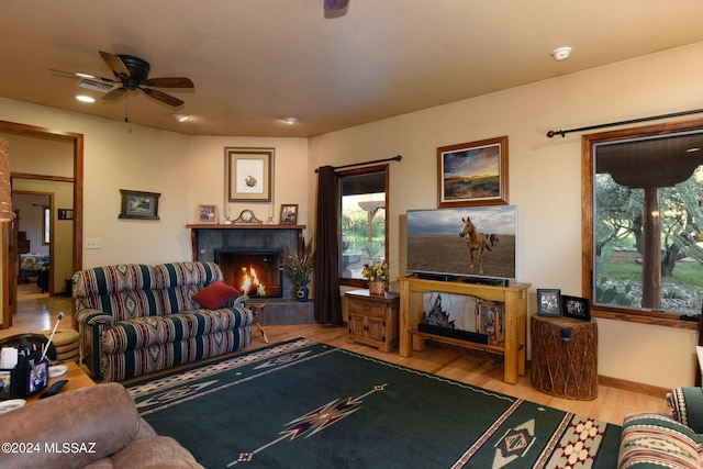 living room featuring ceiling fan, light wood-type flooring, and a fireplace