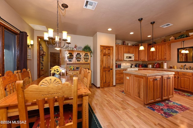 kitchen featuring a chandelier, pendant lighting, white appliances, and a center island