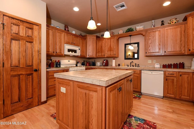 kitchen with light hardwood / wood-style floors, a center island, white appliances, and hanging light fixtures