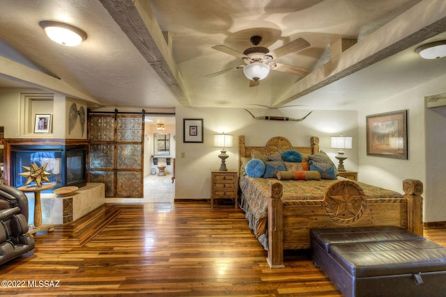 bedroom with a barn door, dark hardwood / wood-style floors, ceiling fan, and lofted ceiling