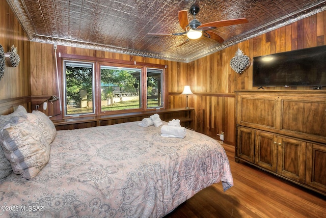 bedroom featuring hardwood / wood-style floors, ceiling fan, and wood walls