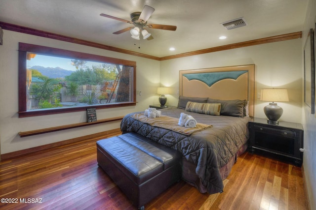 bedroom with a mountain view, hardwood / wood-style flooring, ceiling fan, and crown molding