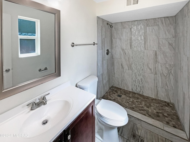 bathroom featuring vanity, toilet, and tiled shower