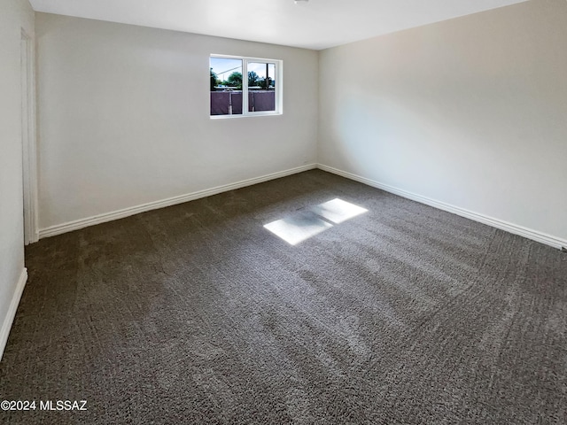 spare room featuring dark carpet