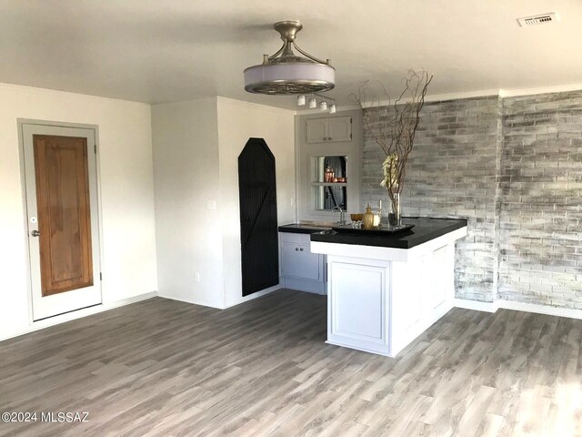 kitchen with tile walls, wood-type flooring, pendant lighting, and kitchen peninsula