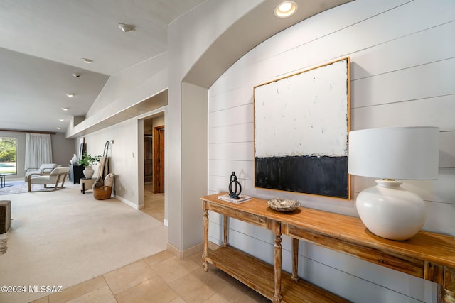 hall with lofted ceiling and light carpet