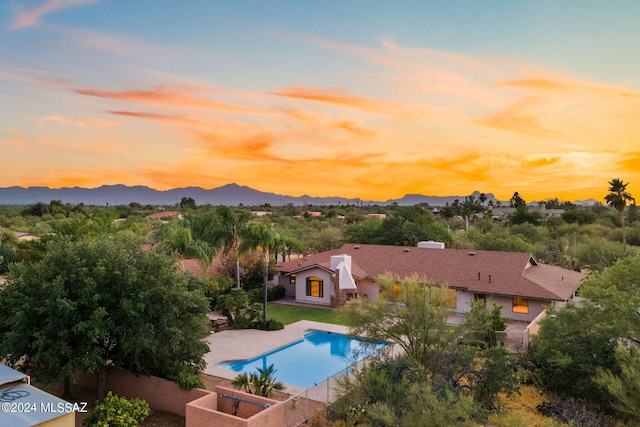 pool at dusk featuring a mountain view and a patio