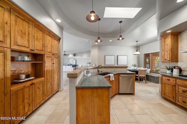 kitchen with pendant lighting, sink, dishwasher, an island with sink, and a raised ceiling