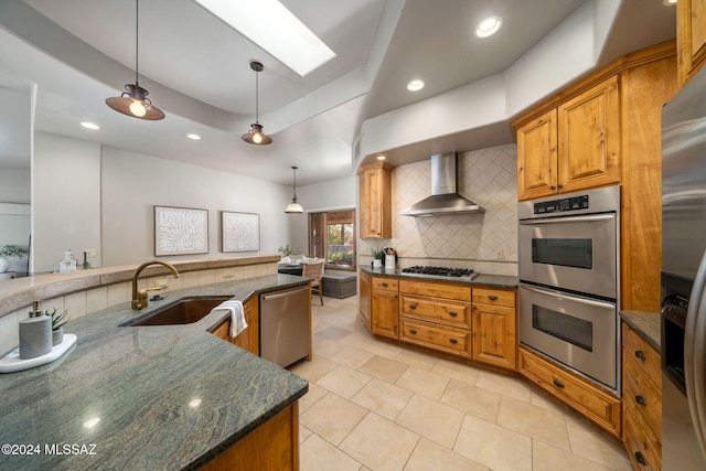 kitchen featuring a raised ceiling, tasteful backsplash, sink, stainless steel appliances, and wall chimney exhaust hood