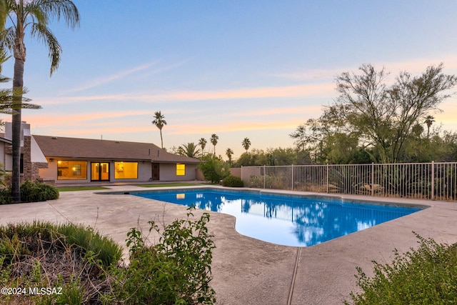 pool at dusk featuring a patio area