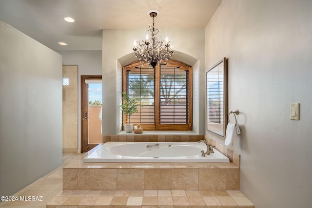 bathroom with an inviting chandelier and tiled bath