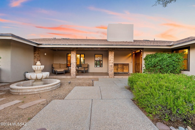 back house at dusk featuring outdoor lounge area and a patio