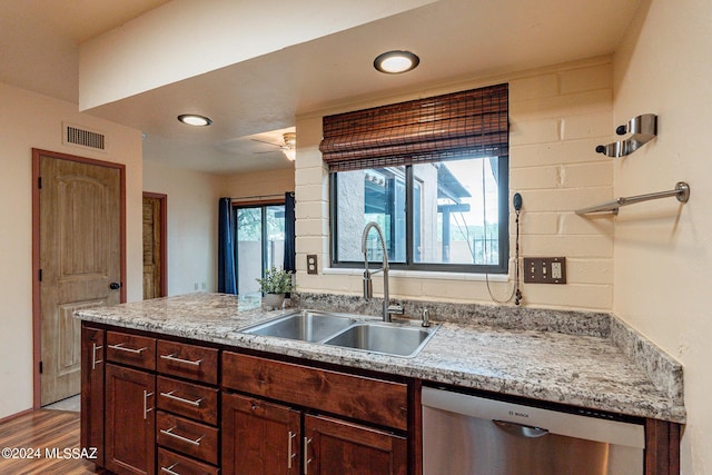 kitchen with visible vents, dishwasher, wood finished floors, a peninsula, and a sink