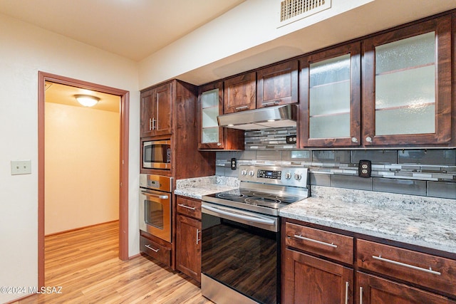 kitchen featuring tasteful backsplash, visible vents, appliances with stainless steel finishes, light wood-type flooring, and under cabinet range hood