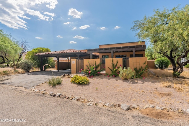 view of front of property with a carport, aphalt driveway, fence, and stucco siding