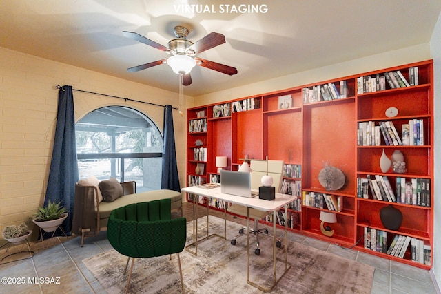 tiled office space with ceiling fan and brick wall