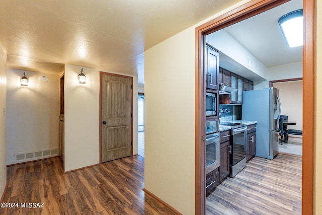 kitchen featuring appliances with stainless steel finishes, wood finished floors, visible vents, and under cabinet range hood