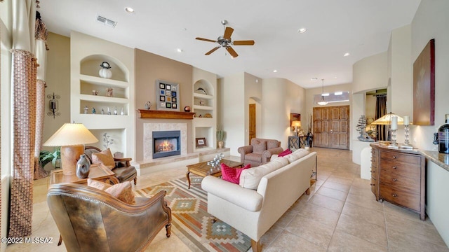 living room with ceiling fan, light tile patterned flooring, built in features, and a fireplace