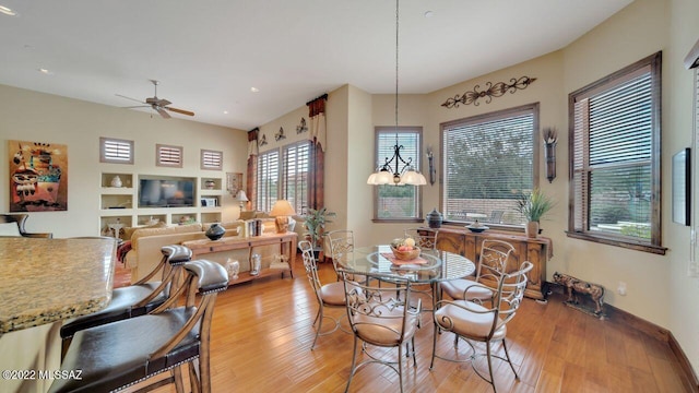 dining space featuring light wood-type flooring and ceiling fan with notable chandelier