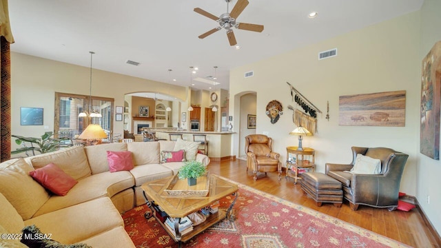 living room with ceiling fan with notable chandelier and light hardwood / wood-style floors