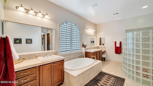 bathroom featuring tile patterned flooring, vanity, and tiled tub