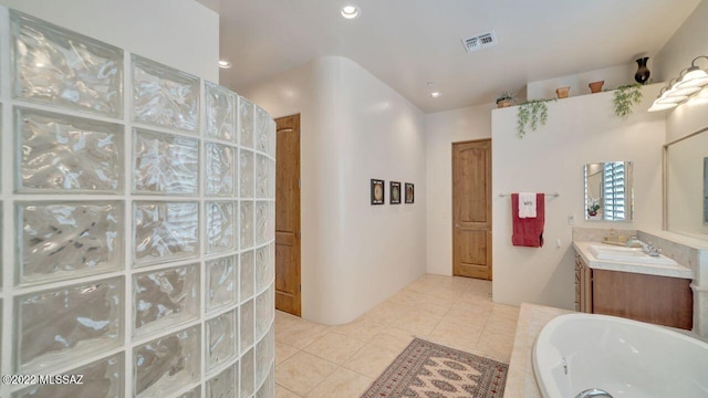 bathroom with a bath, vanity, and tile patterned floors