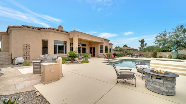 view of pool with ceiling fan, exterior kitchen, an outdoor fire pit, grilling area, and a patio