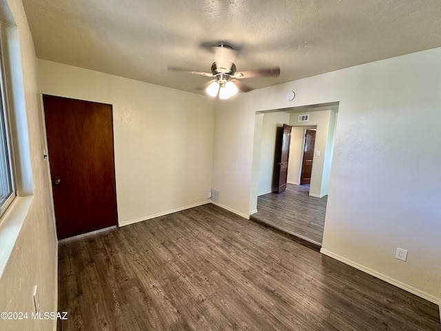 empty room with dark wood-type flooring, a textured ceiling, and ceiling fan