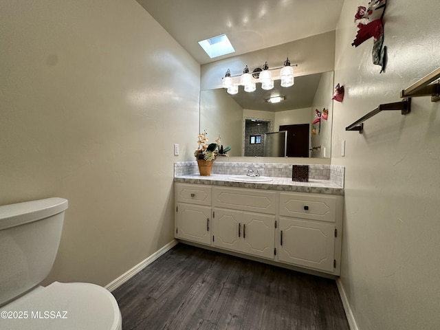 bathroom featuring vanity, wood-type flooring, lofted ceiling with skylight, and toilet