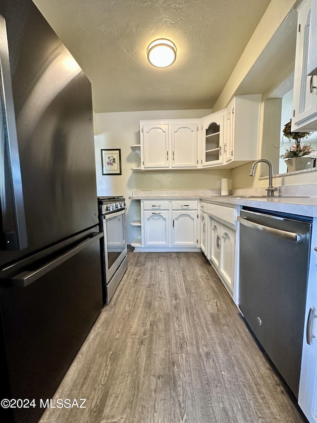 kitchen with white cabinetry, light hardwood / wood-style flooring, a textured ceiling, and appliances with stainless steel finishes