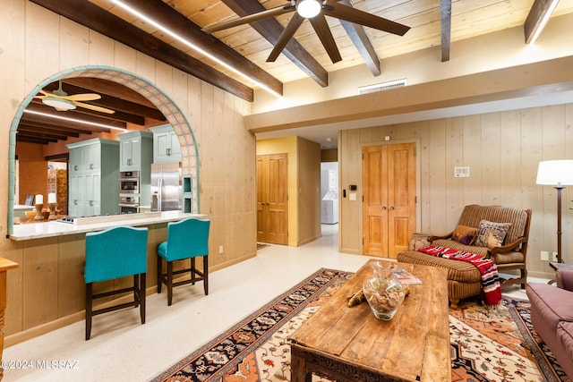 living room featuring wooden ceiling, wood walls, ceiling fan, and beamed ceiling