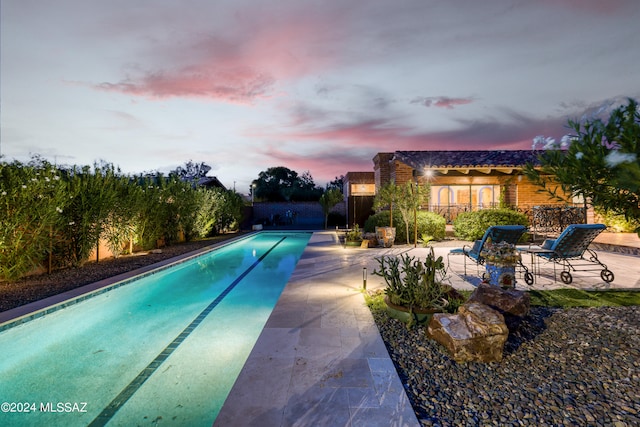 pool at dusk featuring a patio