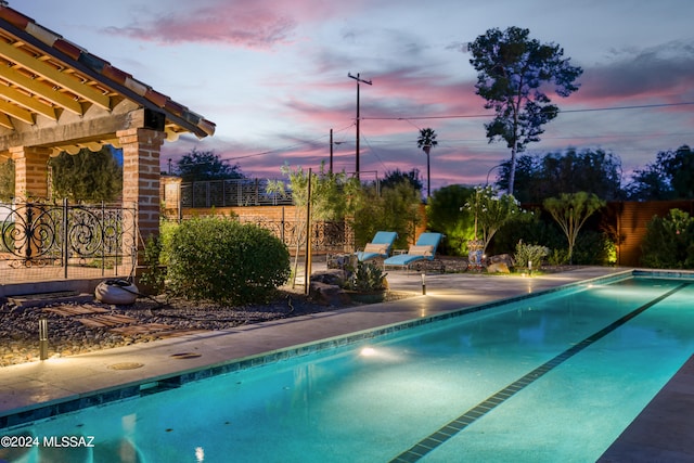 pool at dusk with a patio area