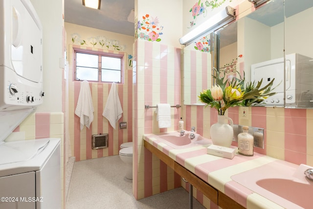 bathroom with tile walls, toilet, vanity, and stacked washing maching and dryer