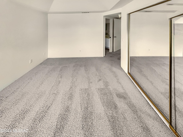 carpeted spare room featuring vaulted ceiling