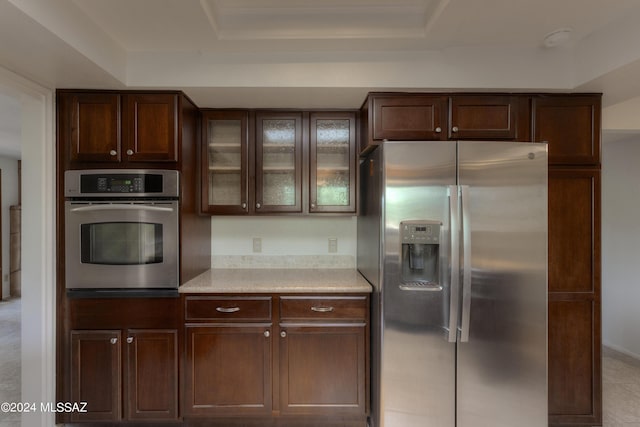 kitchen featuring a raised ceiling, appliances with stainless steel finishes, and dark brown cabinets