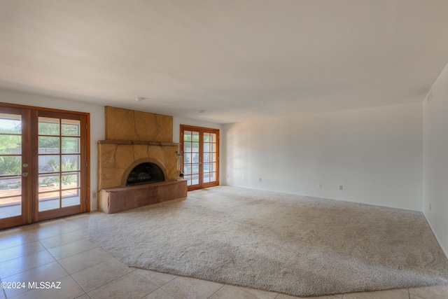 unfurnished living room featuring french doors, light colored carpet, and a fireplace